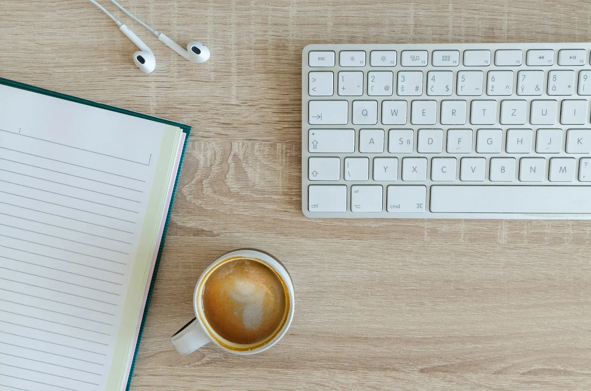 Open notebook, keyboard and a coffee on a wooden desk, ready for planning the December pay runs