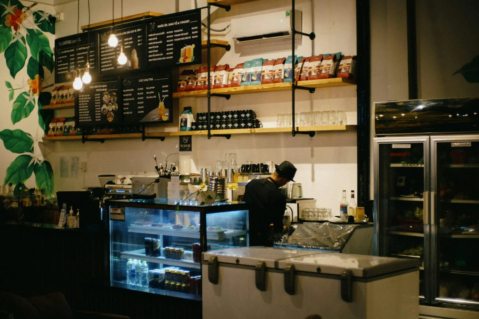 Café owner closing up behind a lit counter at night after a busy weekend of card takings