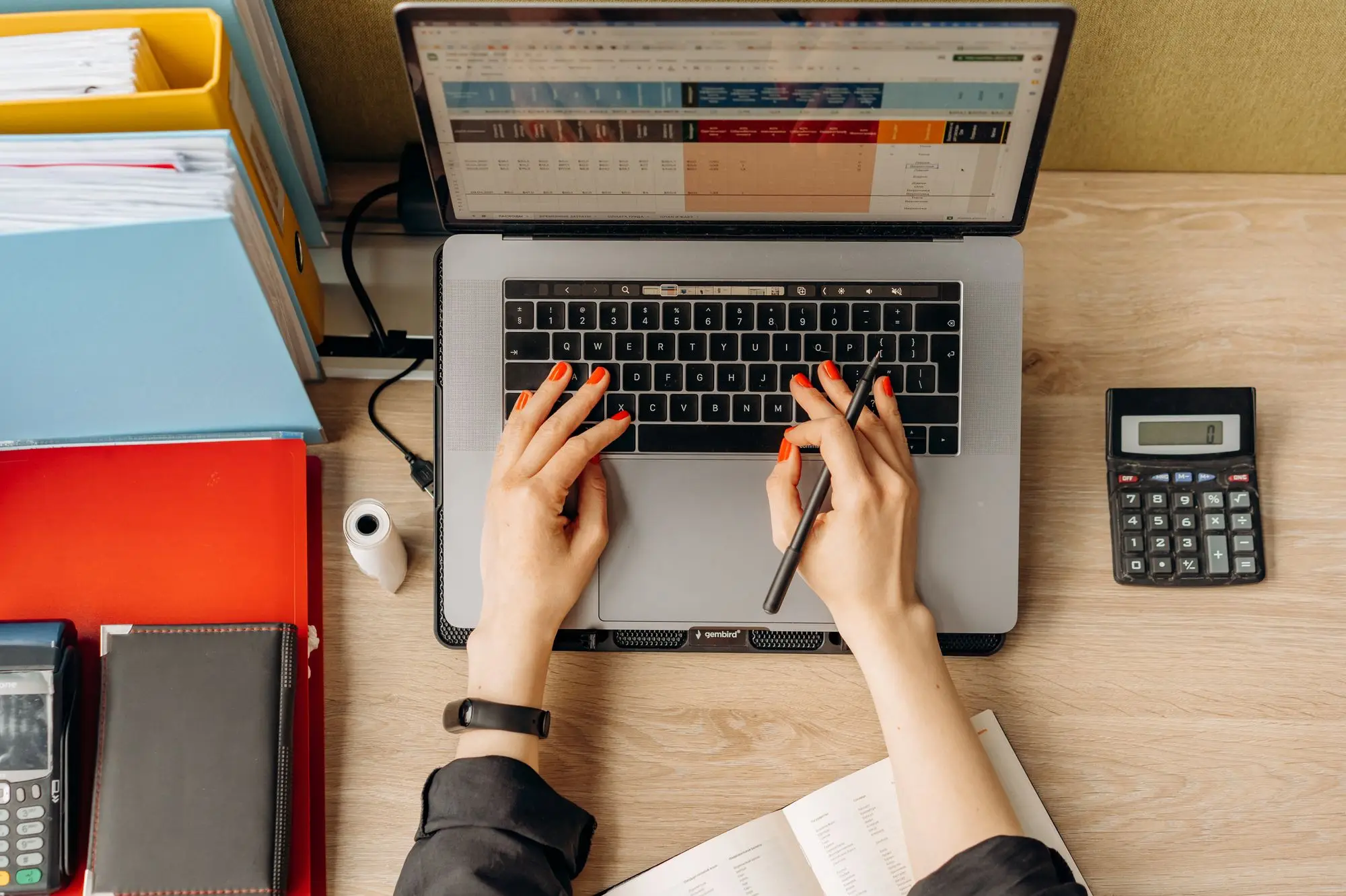 Employer running a payroll spreadsheet on a laptop, with a calculator and card terminal on the desk, before the Christmas pay run
